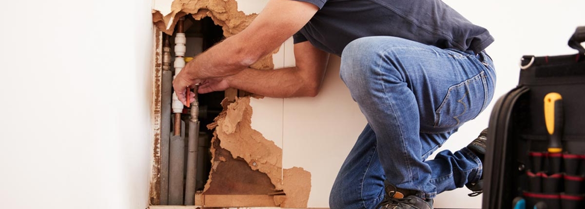 homeguide-plumber-repairing-burst-water-pipe-in-wall homeguide plumber repairing burst water pipe in wall